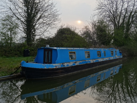 A bright blue narrowboat moored against a canal bank.